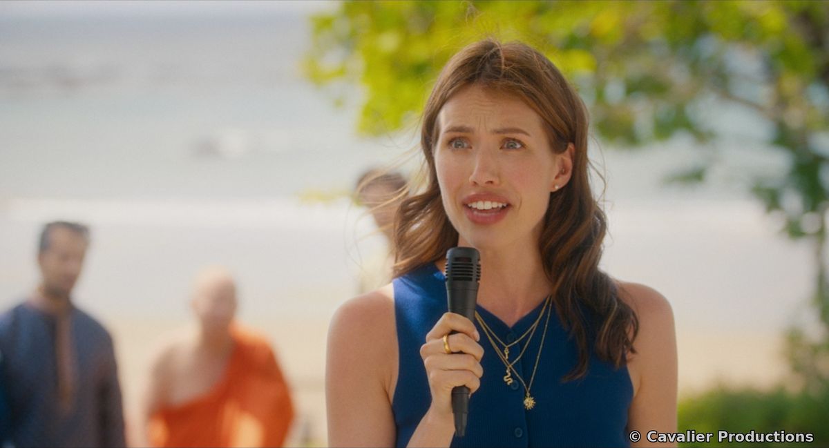 Liz speaking into a microphone at a beach wedding